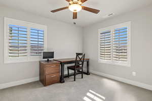 Office with light colored carpet and a ceiling fan