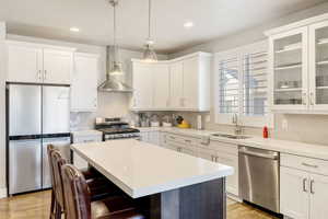 Kitchen featuring stainless steel appliances, white cabinets, decorative light fixtures, a kitchen island, and recessed lighting