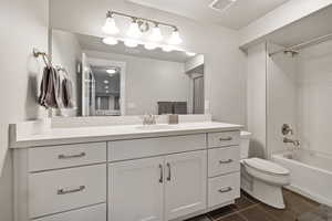 Full bath featuring vanity, shower / bathtub combination with curtain, and dark tile patterned flooring