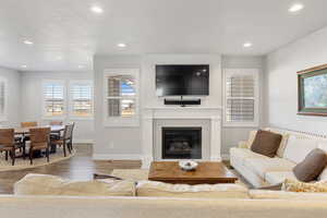 Living area featuring a glass covered fireplace, wood finished floors, recessed lighting, and a textured ceiling
