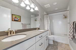 Bathroom featuring double vanity and shower / tub combo with curtain