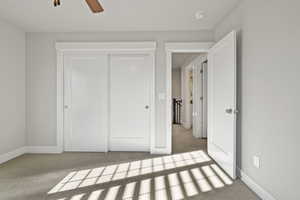 Unfurnished bedroom with carpet, a closet, and a ceiling fan