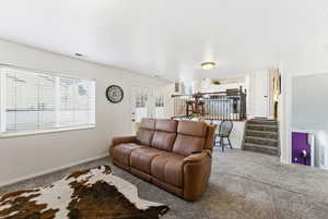 Living room with carpet, stairway, and plenty of natural light