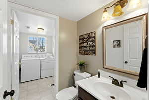 Bathroom with vanity, washer and dryer, and light tile patterned floors