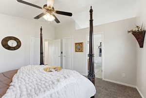 Bedroom featuring carpet flooring, connected bathroom, a ceiling fan, and vaulted ceiling