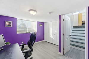 Office area with a textured ceiling and light wood-style flooring