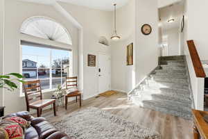 Entryway featuring light wood finished floors, stairway, and a high ceiling