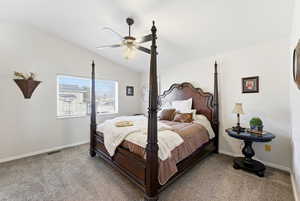 Carpeted bedroom with vaulted ceiling and a ceiling fan