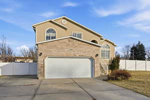View of front of property featuring stucco siding, driveway, brick siding, and an attached garage