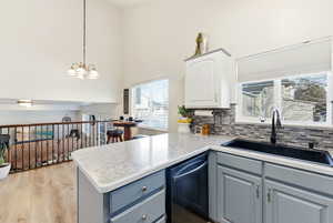 Kitchen with decorative light fixtures, dishwasher, light countertops, tasteful backsplash, and wood finished floors