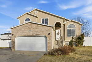 View of front of property featuring concrete driveway, stucco siding, brick siding, and a garage