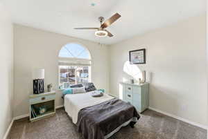 Carpeted bedroom with baseboards and a ceiling fan