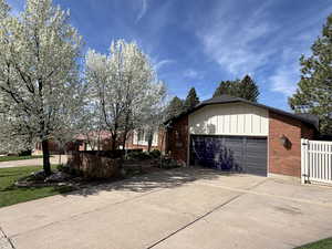 View of home's exterior with an attached garage, concrete driveway, brick siding, a gate, and board and batten siding