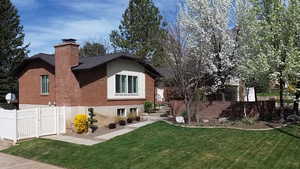 Rear view of house featuring brick siding, a chimney, and a gate