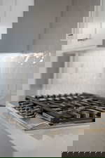 Kitchen view of stainless steel gas stovetop, white cabinets, and tasteful backsplash