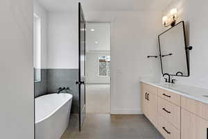 Full bath with dark tile patterned floors, a freestanding tub, vanity, tile walls, and recessed lighting
