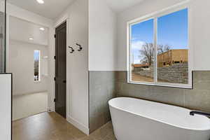 Bathroom featuring tile walls, a freestanding bath, recessed lighting, tile patterned floors, and a wainscoted wall