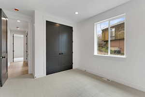 Unfurnished bedroom featuring light carpet, a closet, and recessed lighting