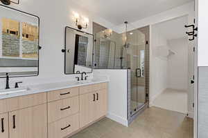 Full bathroom with double vanity, a stall shower, and light tile patterned floors