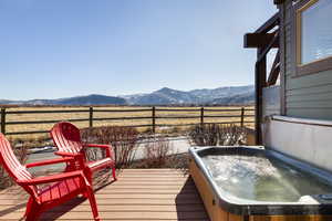 Deck featuring a covered hot tub and a mountain view