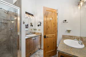 Full bath with two vanities, a shower stall, and light tile patterned floors