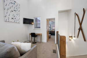 Carpeted living room featuring baseboards and a towering ceiling
