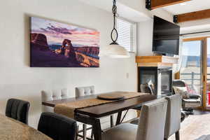 Dining room featuring a glass covered fireplace, beam ceiling, and wood finished floors