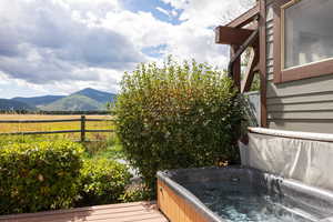 Wooden terrace featuring a mountain view, a view of countryside, and a hot tub
