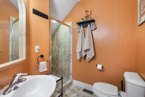 Bathroom with a stall shower, tile patterned flooring, and vaulted ceiling