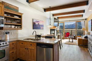 Kitchen featuring a peninsula, stainless steel appliances, pendant lighting, open floor plan, and brown cabinets