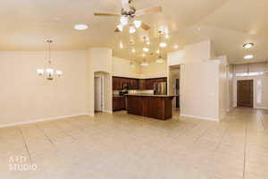 Kitchen with open floor plan, hanging light fixtures, a chandelier, dark brown cabinets, and high vaulted ceiling