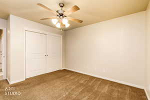 Unfurnished bedroom with a closet, carpet, and a ceiling fan