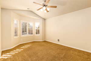 Carpeted empty room with vaulted ceiling and ceiling fan