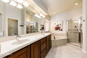 Full bath with lofted ceiling, a stall shower, double vanity, a garden tub, and light tile patterned flooring