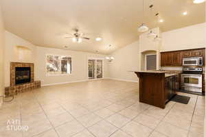 Kitchen with a kitchen bar, open floor plan, hanging light fixtures, appliances with stainless steel finishes, and a tile fireplace