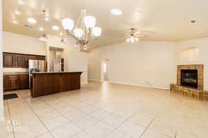 Kitchen with pendant lighting, open floor plan, ceiling fan, a fireplace, and vaulted ceiling