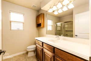 Full bath with vanity, a shower with door, and light tile patterned flooring