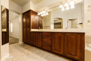Full bath with double vanity, light tile patterned flooring, a garden tub, and a walk in closet
