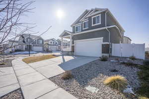 View of front facade with driveway, a residential view, a gate, stucco siding, and a garage