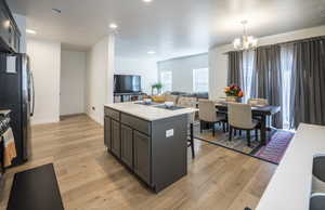 Kitchen with open floor plan, a kitchen island, light wood-style flooring, a chandelier, and a breakfast bar area