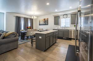 Kitchen featuring stainless steel appliances, a kitchen bar, a center island, a chandelier, and open floor plan