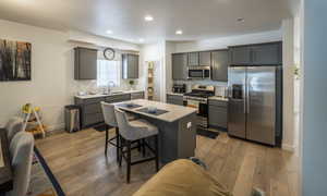 Kitchen featuring appliances with stainless steel finishes, light wood-style floors, a kitchen breakfast bar, a kitchen island, and recessed lighting