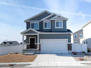 View of front of property featuring covered porch, driveway, a garage, and a gate