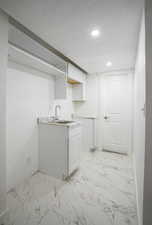 Laundry room featuring light marble finish floors and recessed lighting