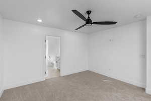 Unfurnished bedroom featuring light carpet, a ceiling fan, and connected bathroom