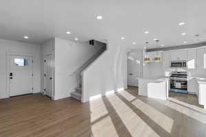 Kitchen with stainless steel appliances, white cabinetry, recessed lighting, a kitchen island, and open floor plan
