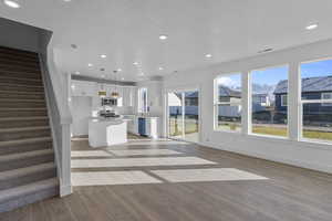 Kitchen with white cabinets, a center island, open floor plan, light wood-style floors, and recessed lighting
