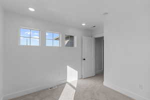 Empty room with light colored carpet and recessed lighting
