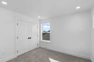 Unfurnished bedroom featuring light carpet, a closet, and recessed lighting