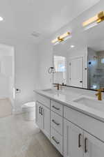 Full bath featuring double vanity, tiled shower, recessed lighting, and light tile patterned floors